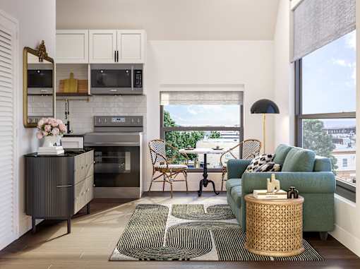 A modern kitchen with a green couch and a dining table.