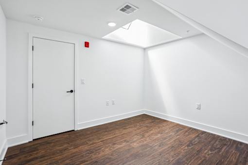 A room with a white door and wooden flooring.