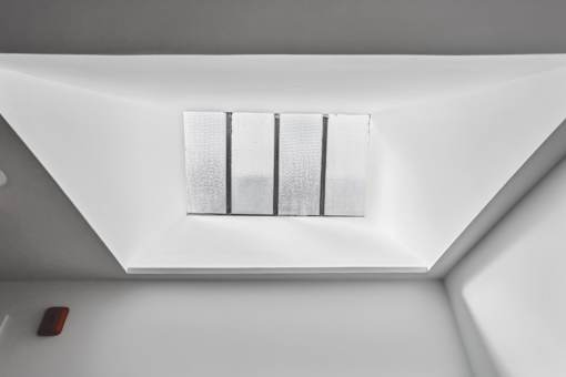A window with a white frame is in the corner of a room.
