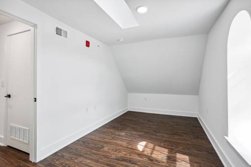 A room with a white door and a window on the right side.