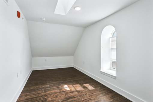A room with a window and a wooden floor.