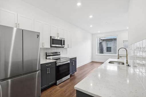 A modern kitchen with stainless steel appliances and a marble countertop.