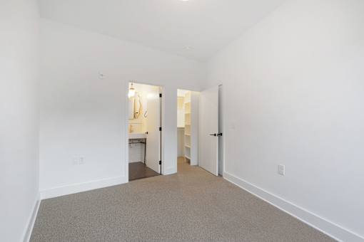 A white room with a carpeted floor and two open doors.