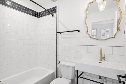 A white bathroom with a black and white tiled shower.