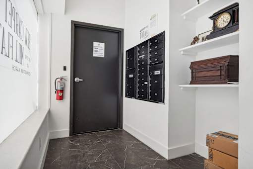 A black door with a sign on it in a room with white walls.