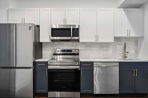 A modern kitchen with dark blue cabinets and stainless steel appliances.