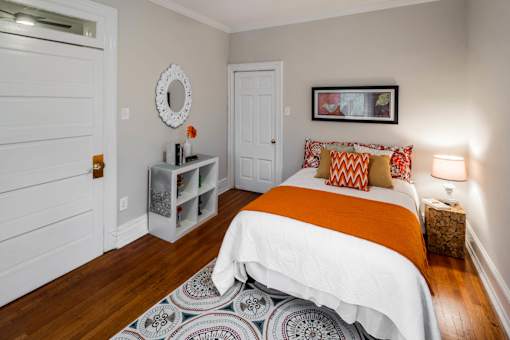 A bedroom with a bed, a wreath, and a picture frame on the wall.