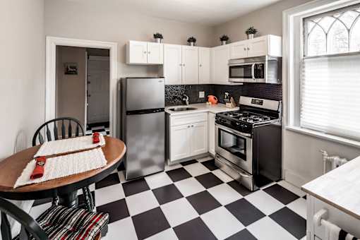 A black and white checkered floor in a kitchen with a refrigerator, oven, and sink.