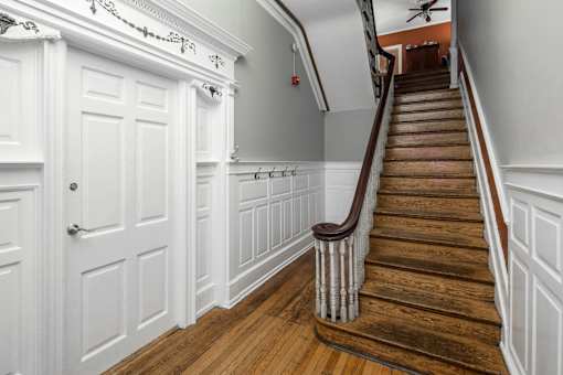 A staircase with a wooden handrail and white walls.