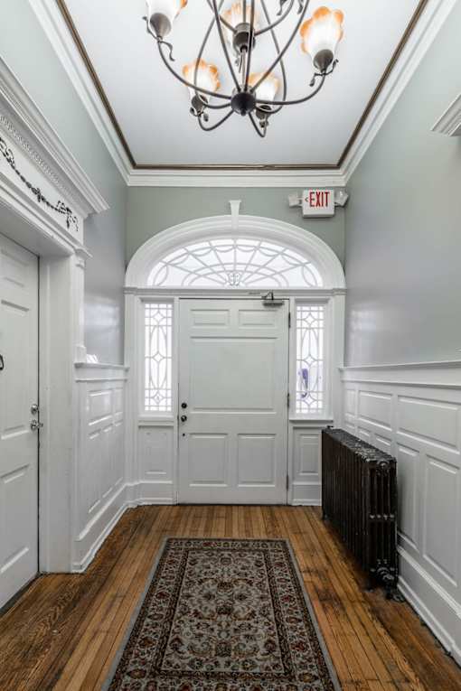 A hallway with a chandelier, a door, and a window.