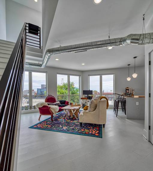 A modern living room with a staircase on the left side.