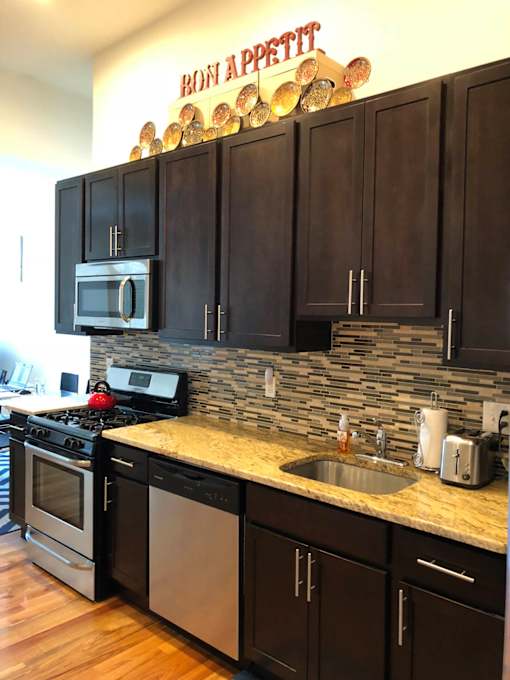 A kitchen with a stone backsplash and wooden cabinets.
