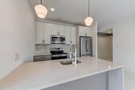 A kitchen with a white countertop and a microwave above it.