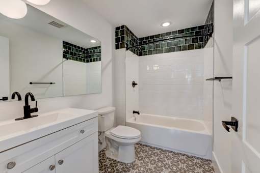 A white bathroom with a black and white tiled shower area.