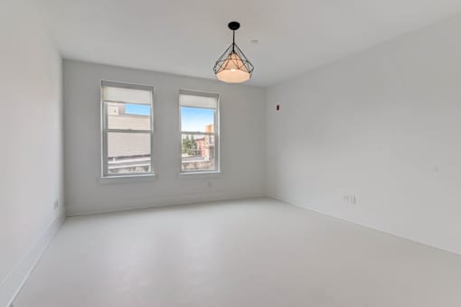 A room with two windows and a hanging light fixture.