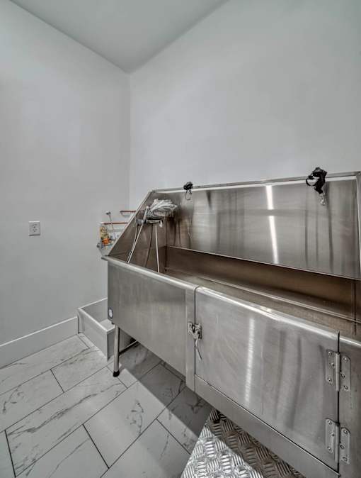 A stainless steel sink in a white room.