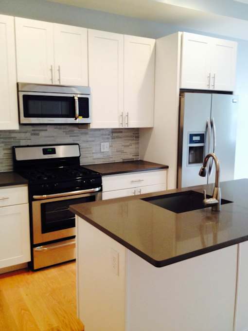A kitchen with white cabinets and a black countertop.