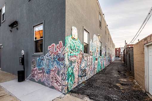 A wall covered in graffiti art on a sidewalk.