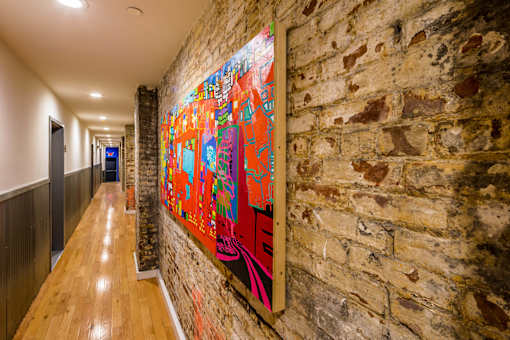 A long hallway with a brick wall and a colorful painting on the wall.