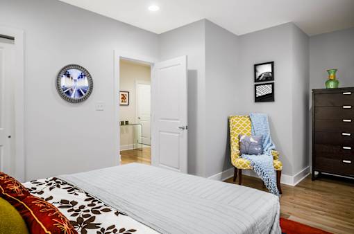 A bedroom with a bed, a chair, and a dresser.