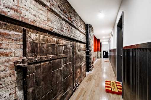 A long hallway with a brick wall on the left and a wooden floor.