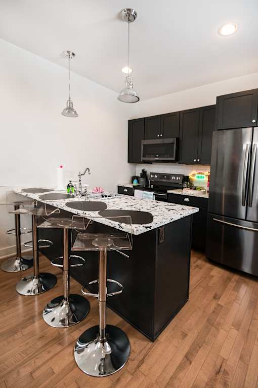 A kitchen with black cabinets and a marble island.