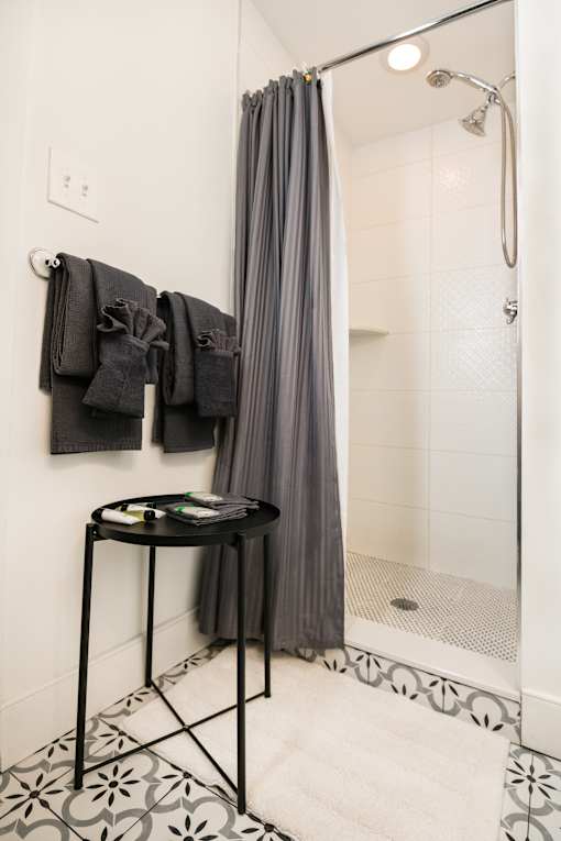 A bathroom with a black table and a grey shower curtain.