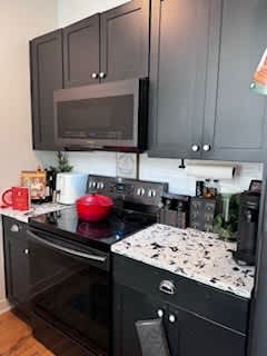 A black and white kitchen with a red pot on the stove.
