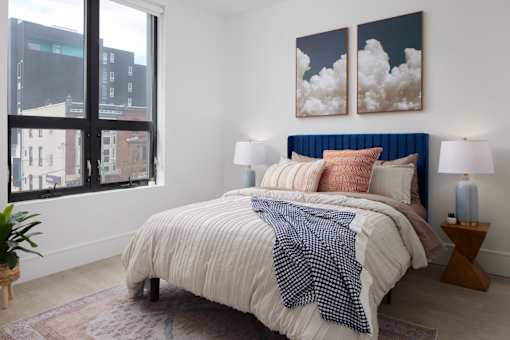 A bedroom with a large bed and two paintings on the wall.