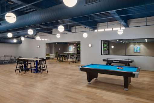 A pool table is in the middle of a room with a bar and a ping pong table.
