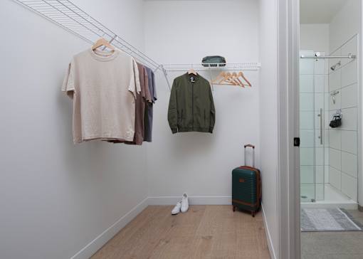 A white wall with clothes hanging and a suitcase on the floor. at 1600 Callowhill, Philadelphia, PA