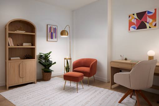 A room with a red chair, a wooden shelf, and a desk with a lamp. at 1600 Callowhill, Philadelphia, PA