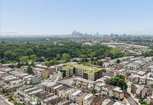 A cityscape with a mix of residential and commercial buildings, with a clear sky and a distant city skyline.