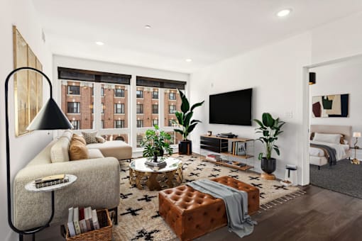 A modern living room with a brown leather ottoman and a grey sofa.