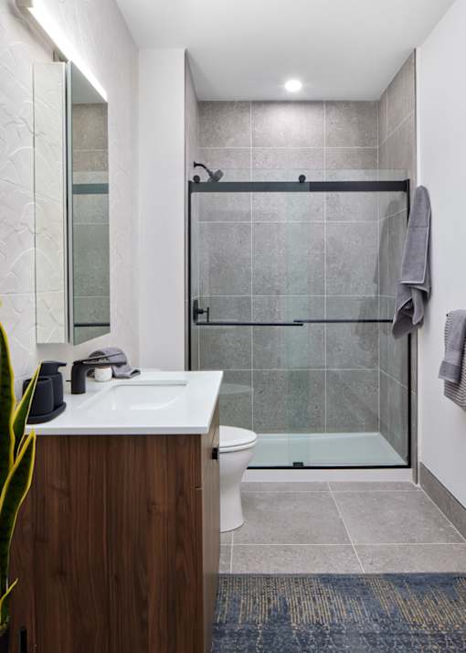 A modern bathroom with a walk-in shower and a white sink.