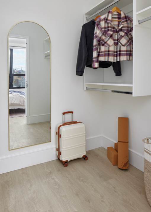 A white suitcase is on the floor next to a wall-mounted closet.