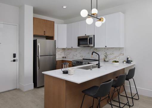 A kitchen with a white countertop and black chairs.