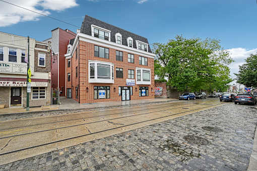 A cobblestone street with a building on the right and a car parked on the street.