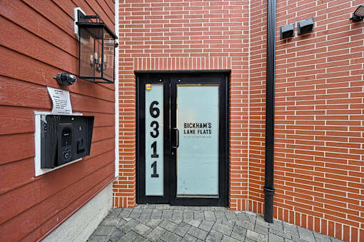 A red building with a black door that has a sign on it.