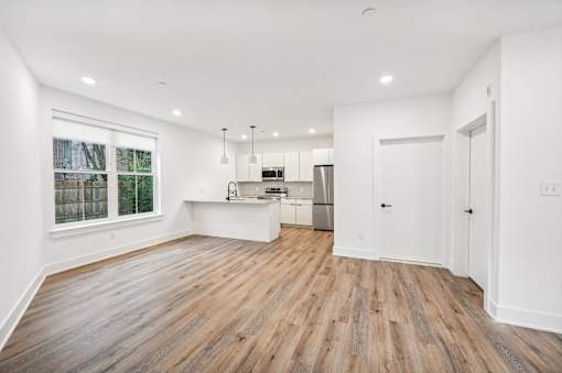 A spacious kitchen with wooden floors and white walls.