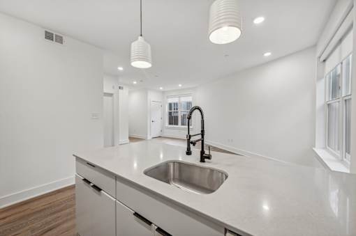 A modern kitchen with a white countertop and a stainless steel sink.
