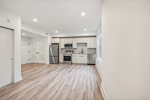 A kitchen with white cabinets and a wooden floor.