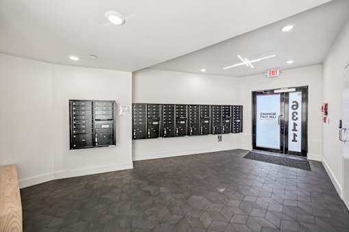 A room with a black tiled floor and a white wall with a row of lockers on it.