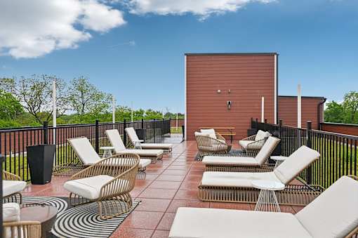 A patio with chairs and a table with a black trash can.