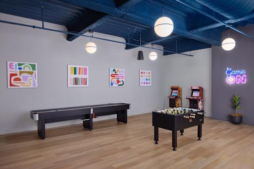 A room with a pool table and a neon sign that says "Game On".