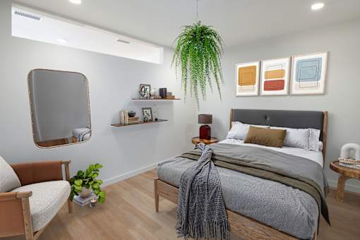 A bedroom with a bed, chair, and potted plant.