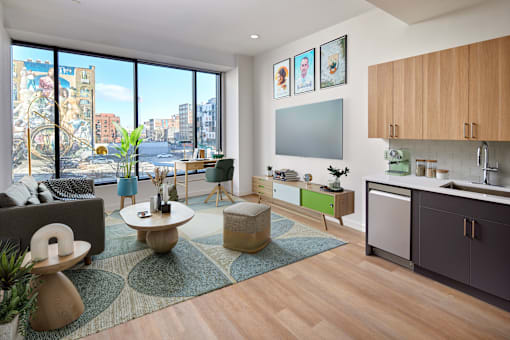 A living room with a couch, a coffee table, and a large window overlooking a city.
