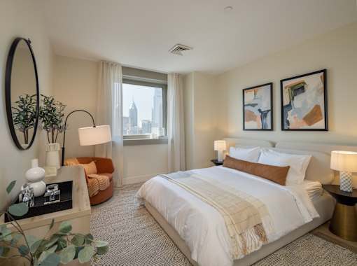 A bedroom with a large bed, a round mirror, and a view of the city.