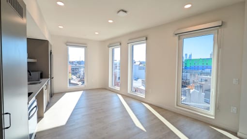 an empty living room with large windows and a city view