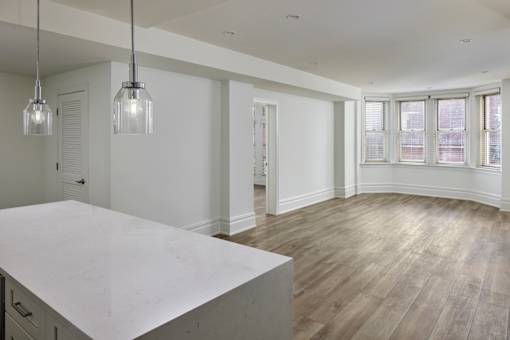 A large, empty room with a marble countertop and wooden flooring.